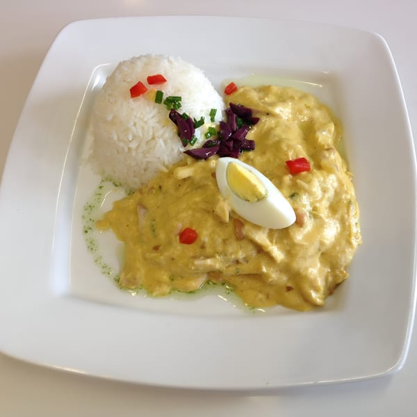 Peruvian Aji de Gallina with rice, red peppers, olives, chives, and a hard-boiled egg.