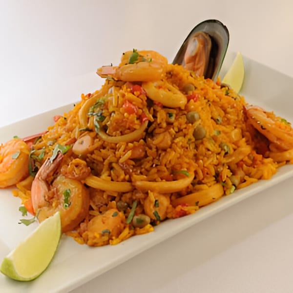 Peruvian arroz con mariscos, a seafood rice dish with shrimp, calamari, mussels, and lime wedges.