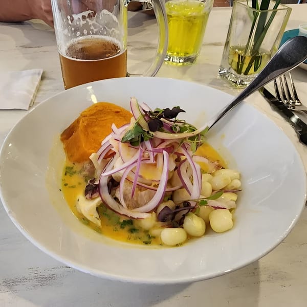 Peruvian ceviche with red onions, corn, and sweet potato, served with a beer.