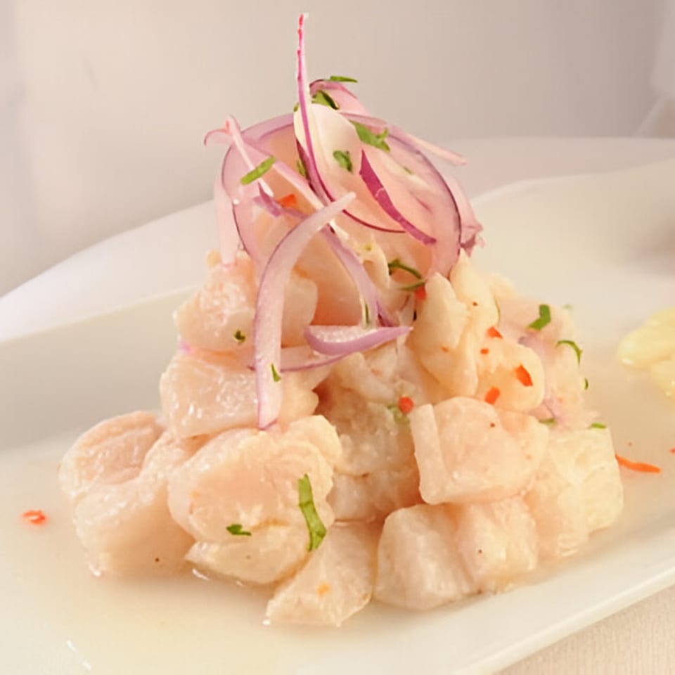 Peruvian ceviche with white fish, red onions, and cilantro on a white plate at El Pollo Inka Miami.
